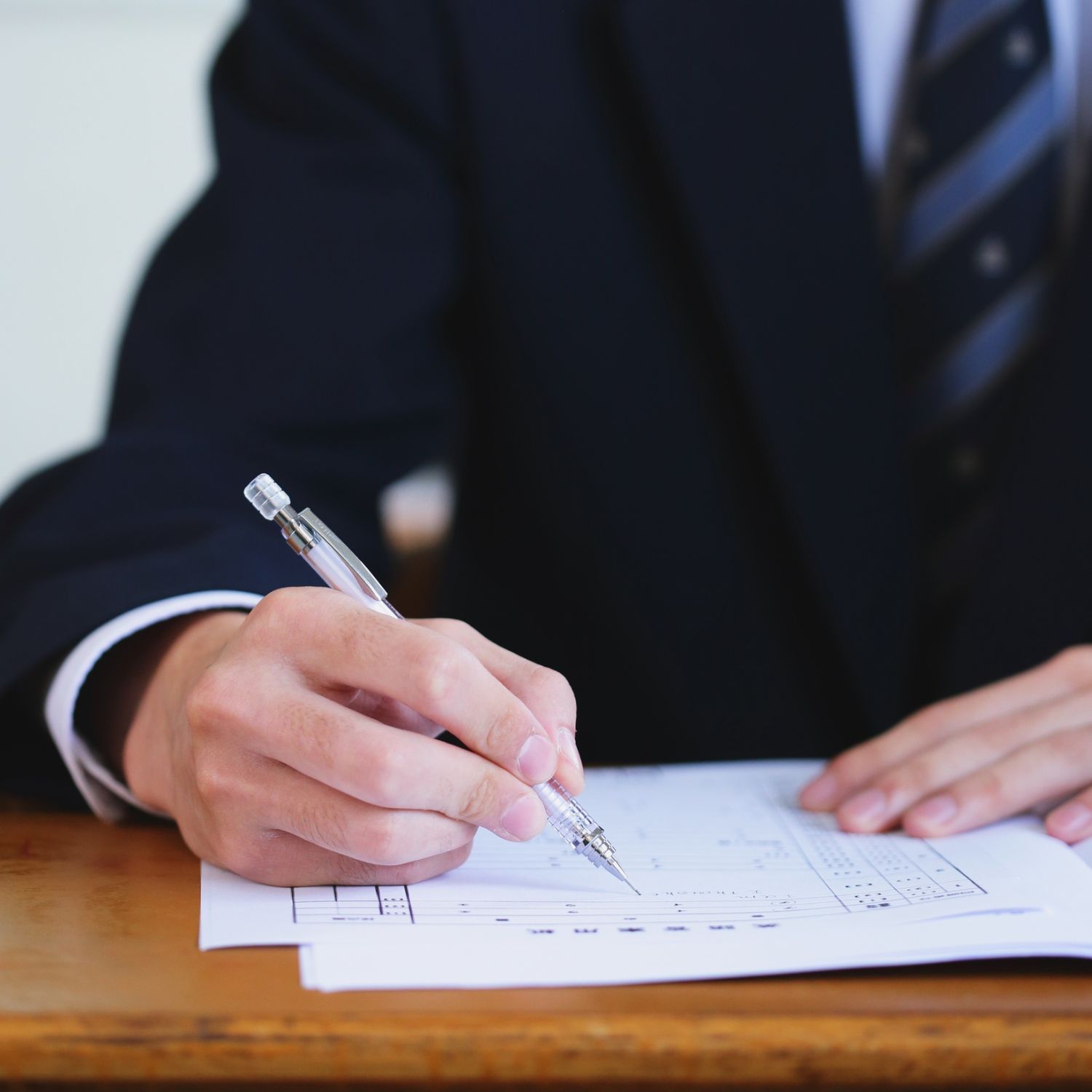 high-stakes-exam-accommodations-evaluation-student-taking-test Adult man in a suit taking an exam, representing support for high-stakes testing accommodations.